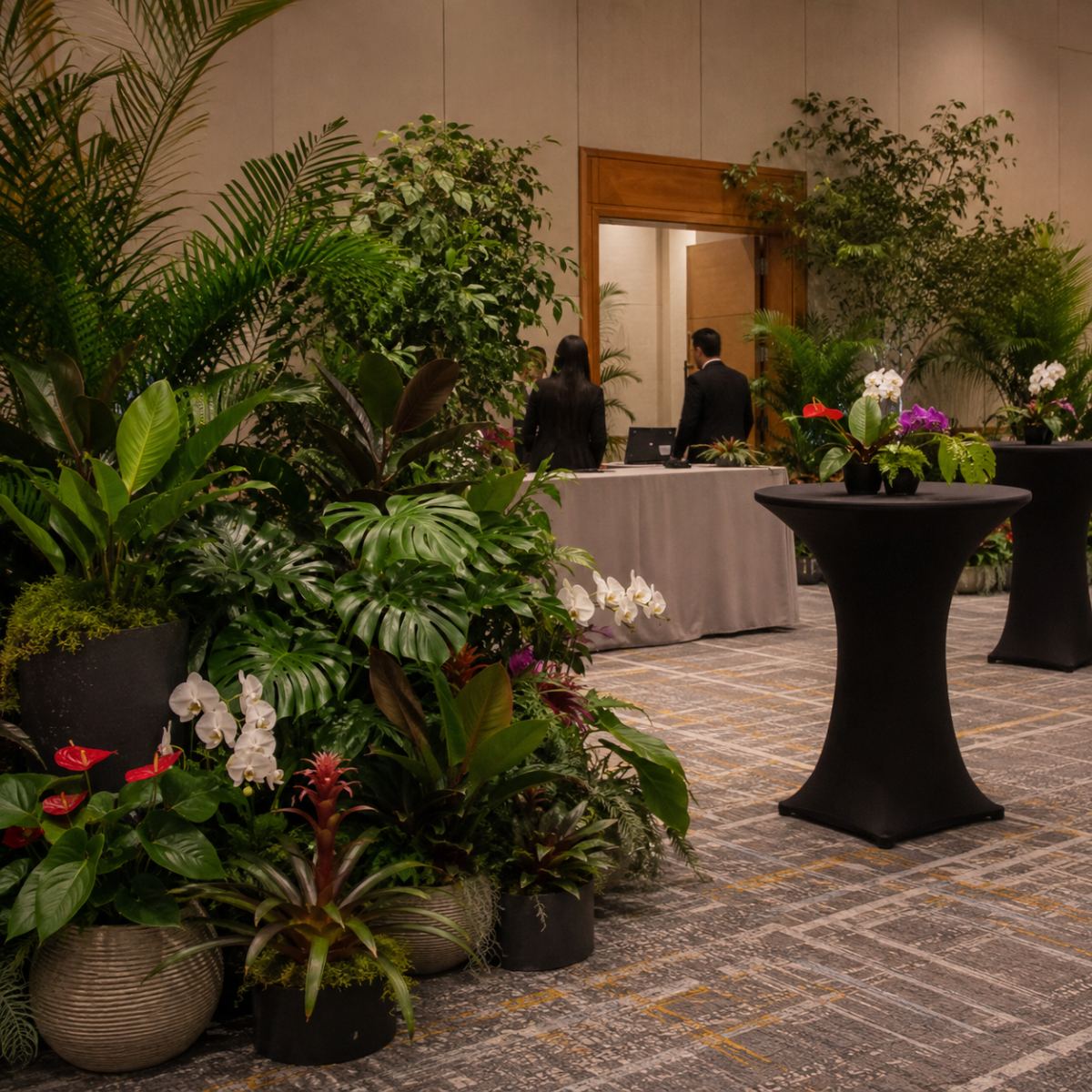 Mesa de recepción de un evento rodeada de palmas, monsteras, orquídeas y bromelias en maceta